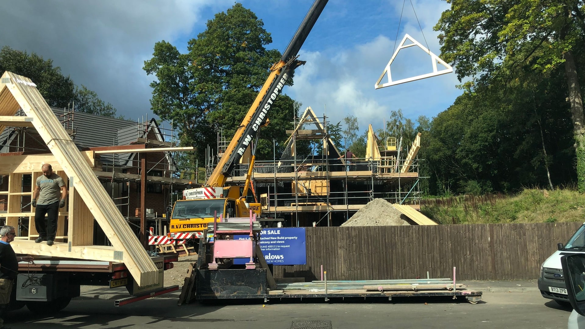 A crane lifting timber frames on a C&M Developments housing site