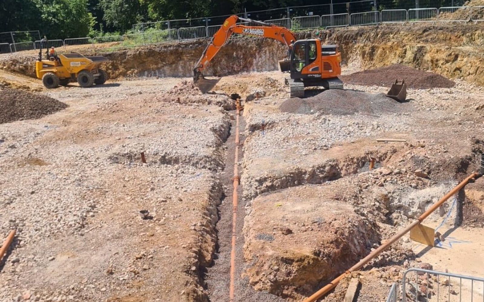 Excavator digging a drainage trench on a cleared site